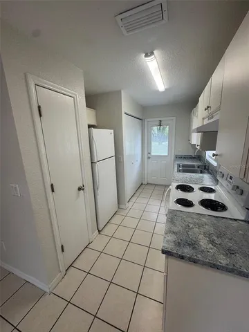 a kitchen with granite countertop a sink a stove a refrigerator and cabinets