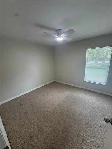 an empty room with windows and fan