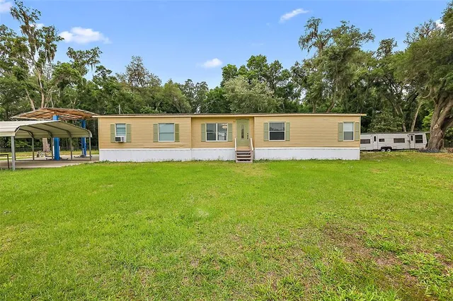 a front view of house with yard and trees in the background