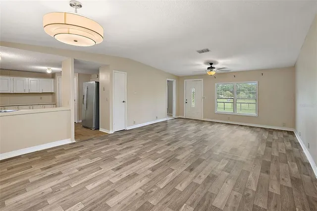 an empty room with wooden floor cabinet and windows