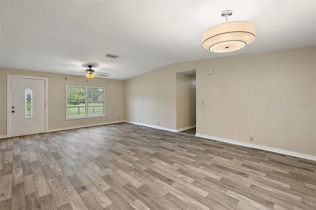 an empty room with wooden floor cabinet and windows