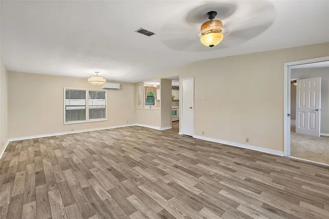 a view of an empty room with window and wooden floor