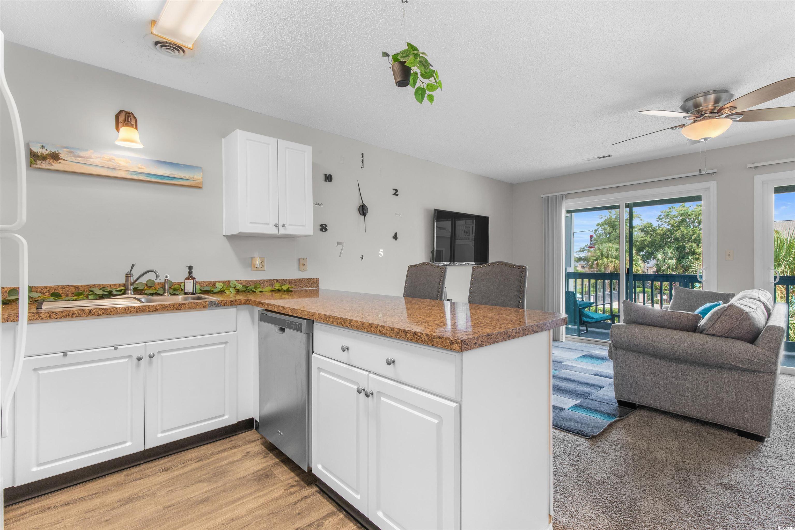 1850 Colony Drive, Unit 3D Surfside Beach, SC 29575 - Photo 37 of 38 Kitchen with a peninsula, white cabinetry, open floor plan, stainless steel dishwasher, and a ceiling fan