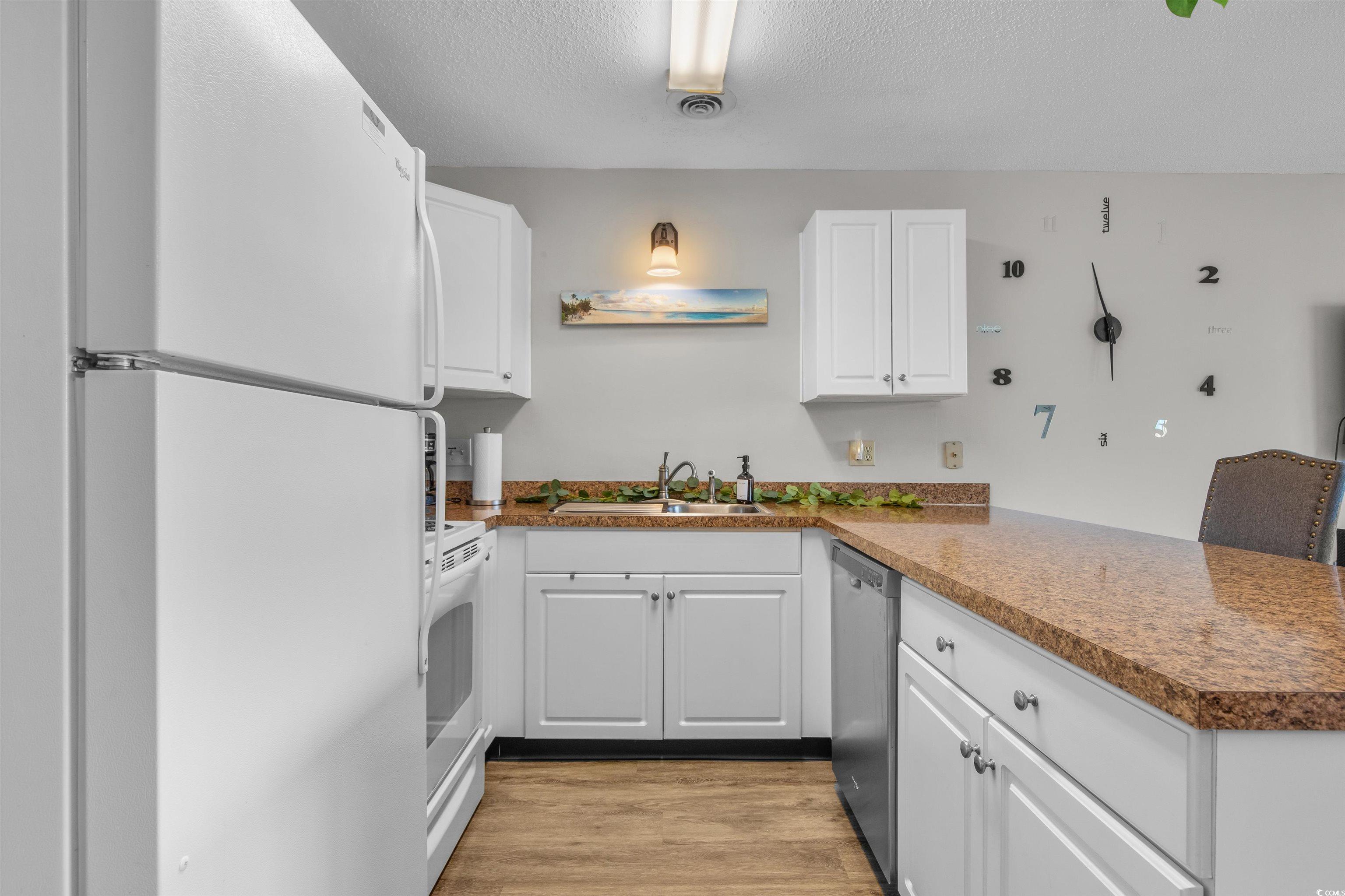 1850 Colony Drive, Unit 3D Surfside Beach, SC 29575 - Photo 14 of 38 Kitchen featuring white appliances, white cabinets, a textured ceiling, and light wood finished floors
