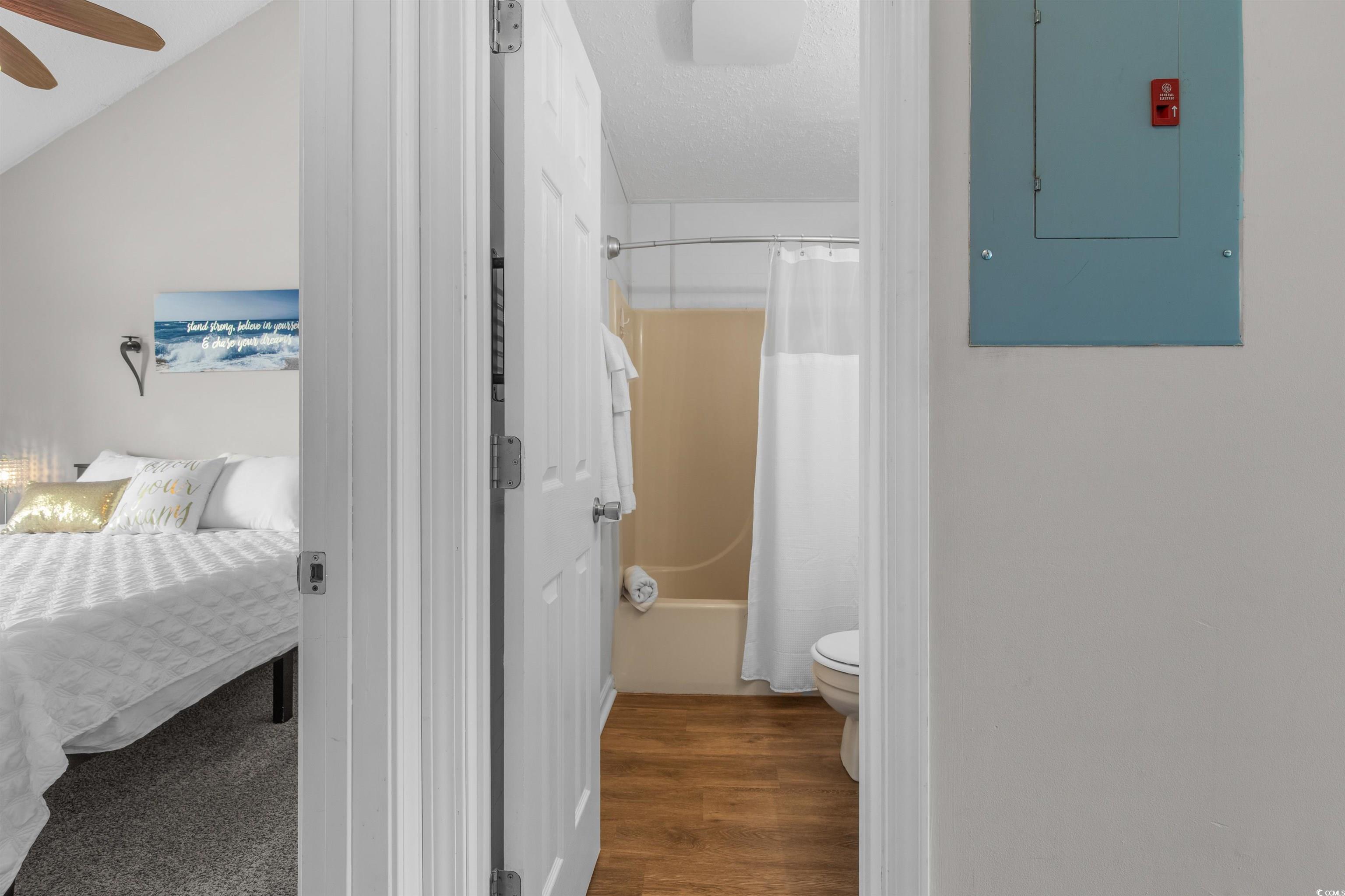 1850 Colony Drive, Unit 3D Surfside Beach, SC 29575 - Photo 3 of 38 Bathroom featuring electric panel, shower / bath combination with curtain, dark wood finished floors, and a textured ceiling