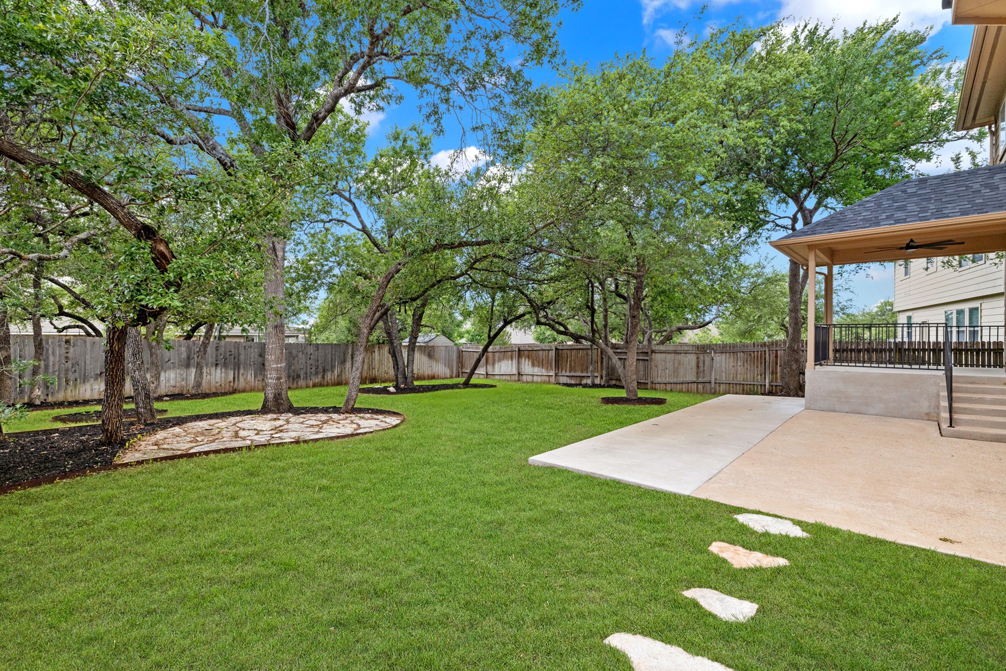 403 Red Hawk Drive Leander, TX 78641 - Photo 30 of 37 Expansive backyard featuring a lush lawn, mature shade trees, a flagstone patio area, and a covered porch with a ceiling fan
