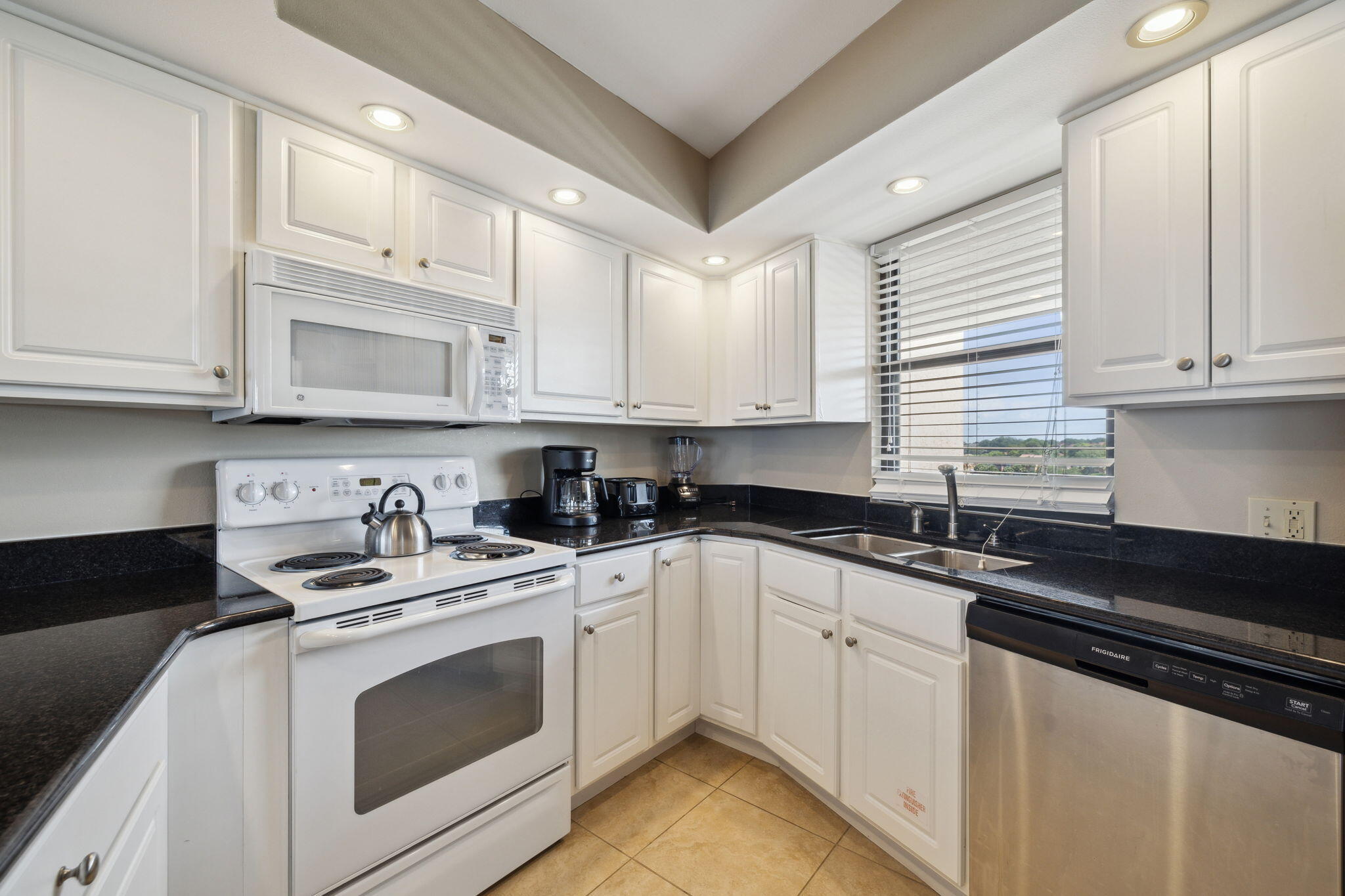 4072 Beachside 1, Unit 4072 Miramar Beach, FL 32550 - Photo 15 of 75 a kitchen with granite countertop white cabinets sink and white appliances