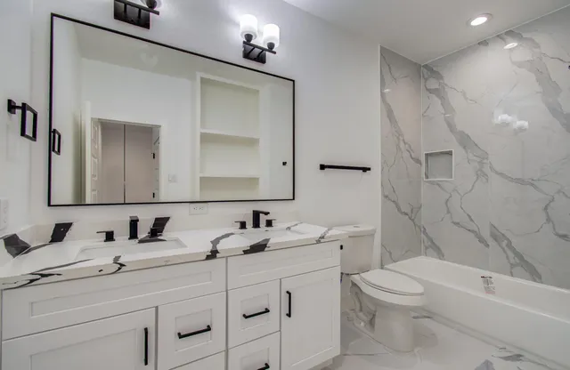 a bathroom with a toilet sink double vanity and bathtub