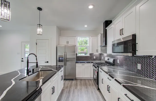 a kitchen with granite countertop a sink stainless steel appliances and cabinets