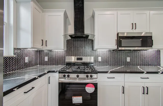 a kitchen with stainless steel appliances granite countertop a stove a sink and a microwave