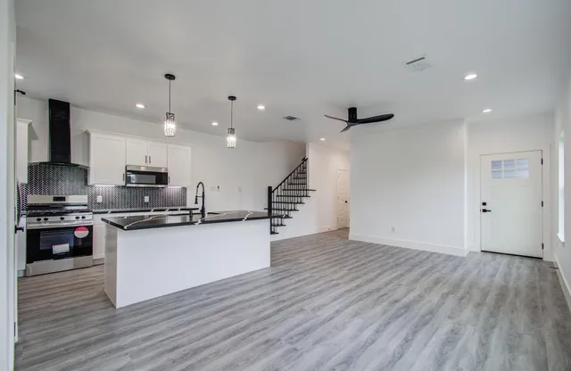a kitchen with stainless steel appliances granite countertop a stove and a wooden floors