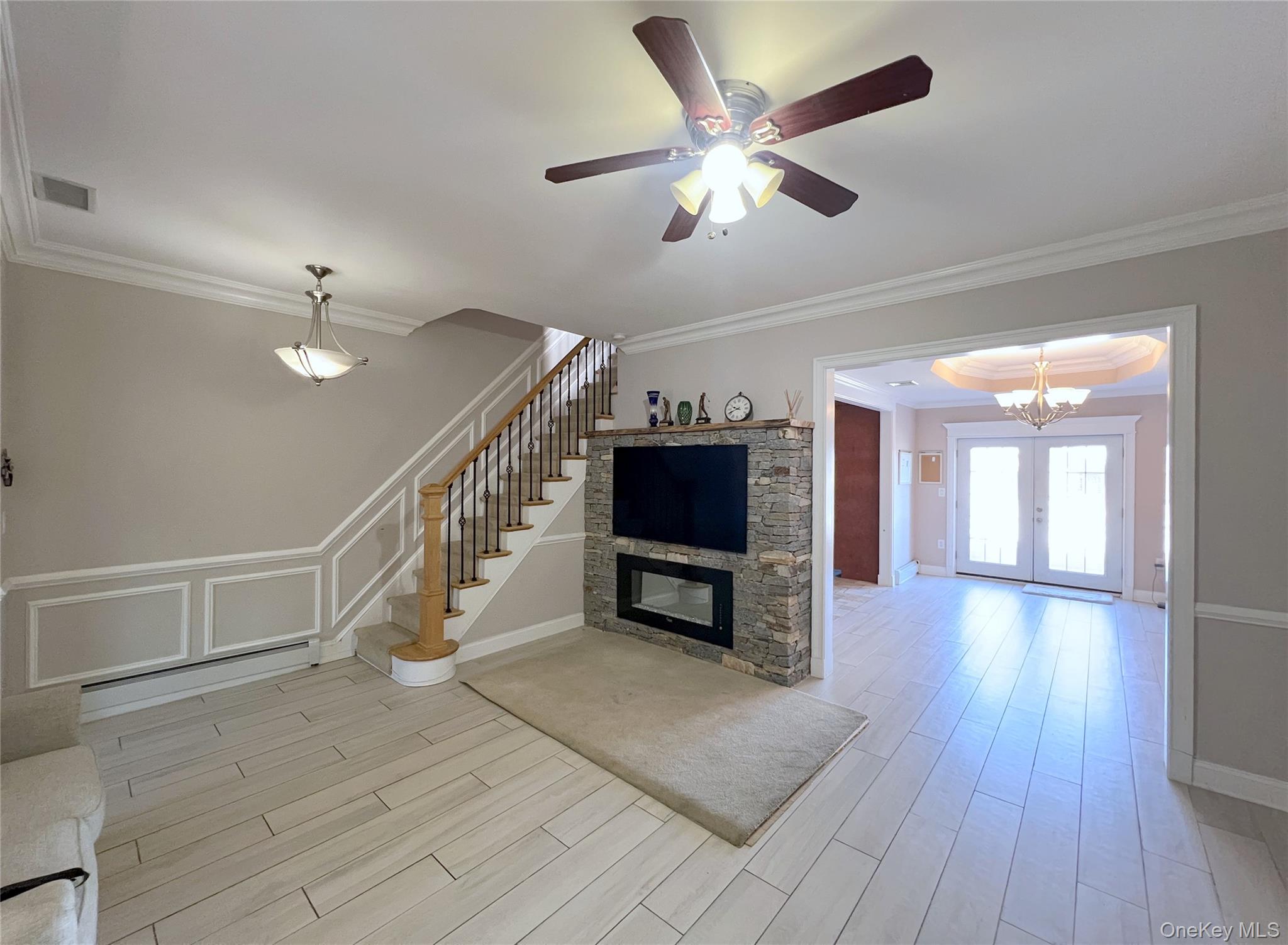 67-31 52nd Road Queens, NY 11378 - Photo 4 of 21 Unfurnished living room with ornamental molding, light wood finished floors, stairway, a fireplace, and a chandelier