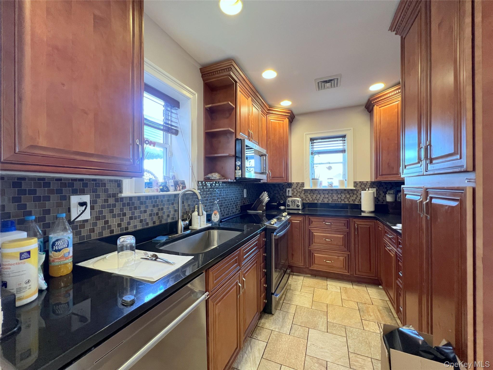 67-31 52nd Road Queens, NY 11378 - Photo 5 of 21 Kitchen featuring open shelves, stainless steel appliances, decorative backsplash, recessed lighting, and dark stone counters