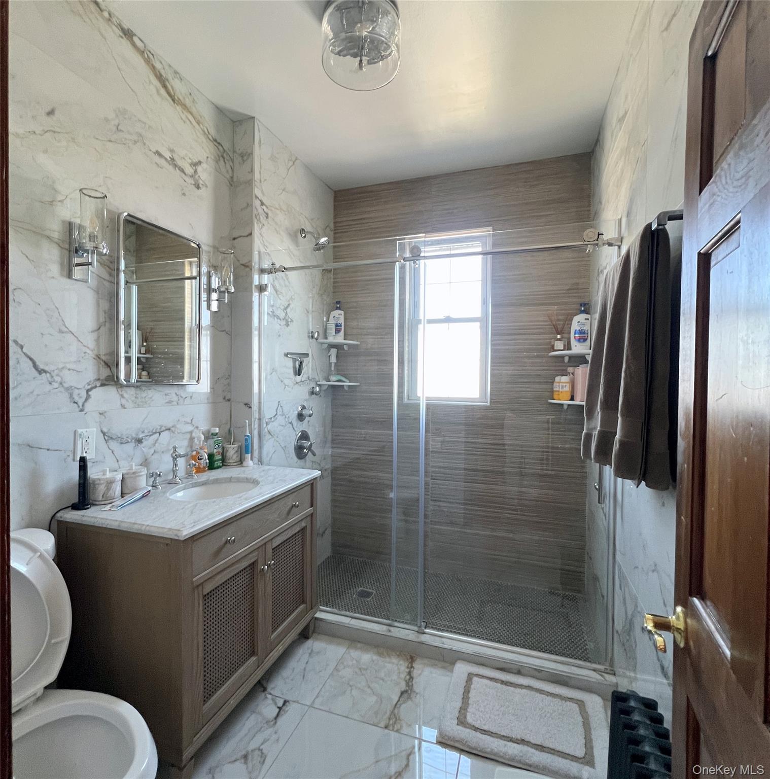 67-31 52nd Road Queens, NY 11378 - Photo 6 of 21 Bathroom featuring light marble finish flooring, vanity, a stall shower, and tile walls