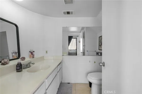 a bathroom with a granite countertop sink toilet and mirror
