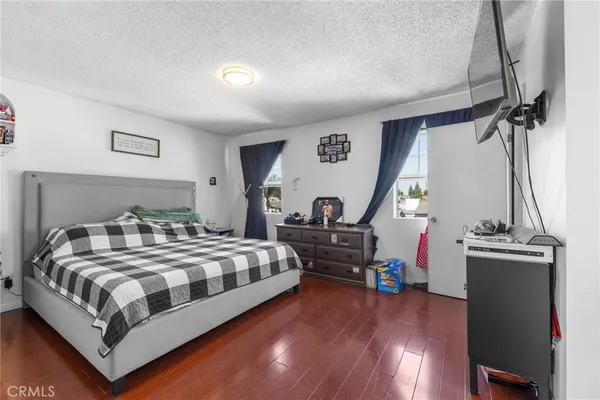 a bedroom with a bed and a flat tv screen on dresser