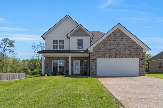 a view of a house with brick walls and a yard with plants