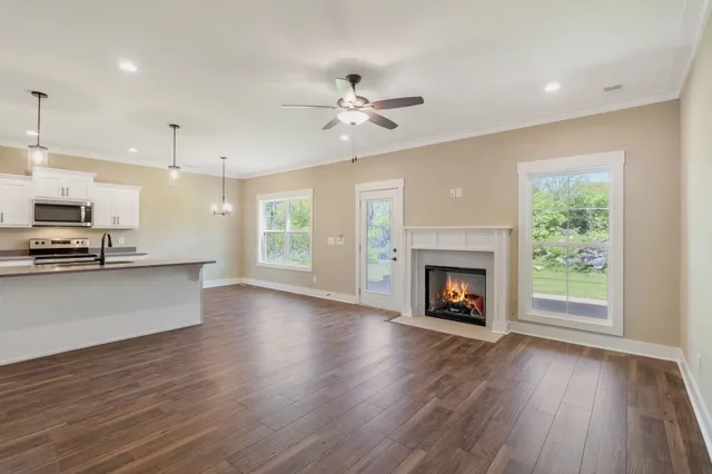 an open kitchen with a fireplace a ceiling fan and wooden floor