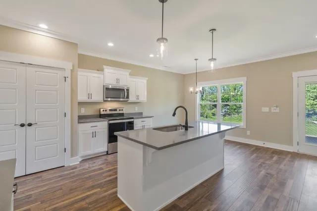 a kitchen with granite countertop a sink appliances wooden floor and a window