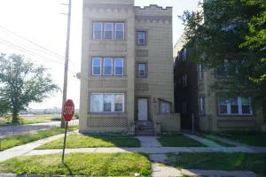 a house in front of a brick house with large windows and a small yard