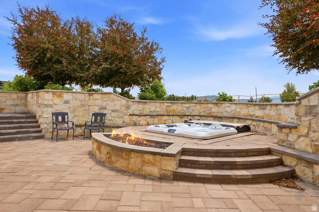 71 Farm Road Midway, UT 84049 - Photo 81 of 92 Spacious paver patio featuring a built-in fire pit, integrated hot tub, and stacked stone retaining walls
