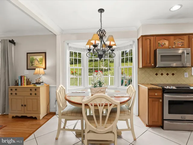 a view of a dining room with furniture a chandelier and large windows