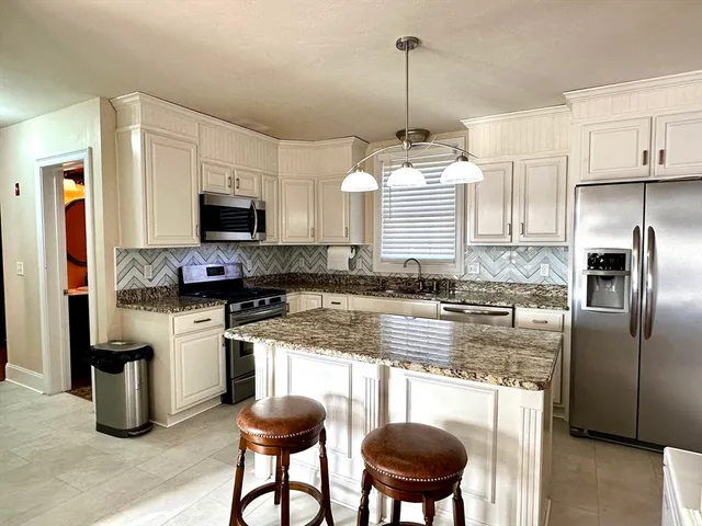 a kitchen with stainless steel appliances granite countertop a stove a sink and a refrigerator