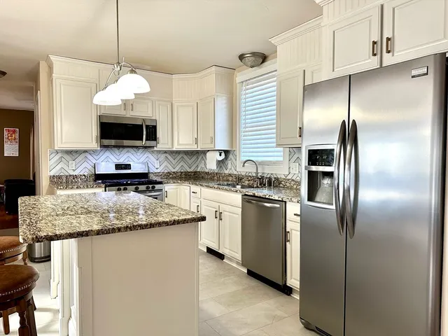 a kitchen with stainless steel appliances granite countertop a refrigerator a stove a sink and a microwave