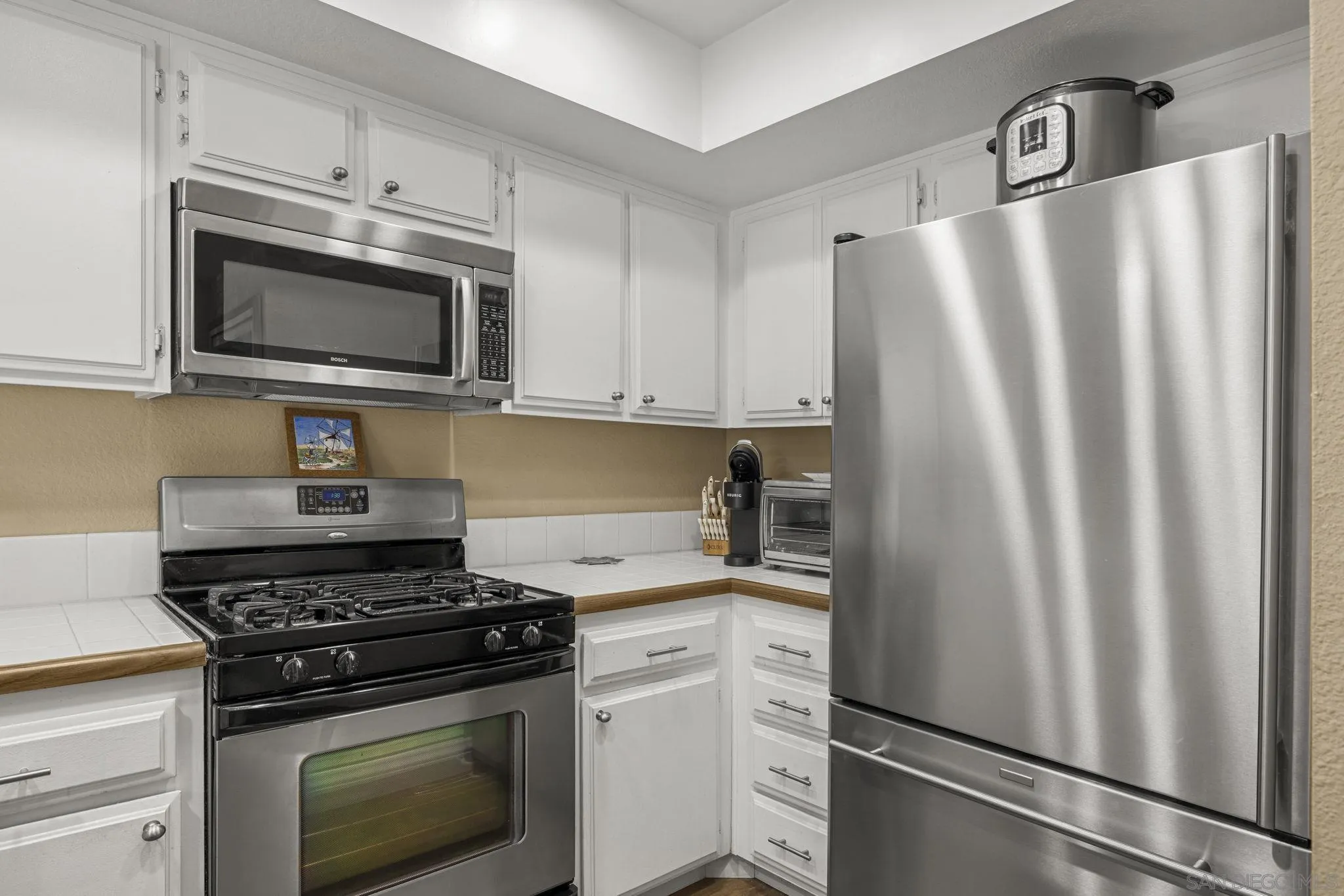 883 Ginger Avenue Carlsbad, CA 92011 - Photo 14 of 33 a kitchen with stainless steel appliances white cabinets white stove a microwave and a refrigerator