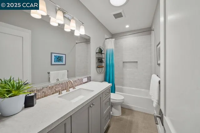 a bathroom with a granite countertop sink a toilet a large mirror and shower