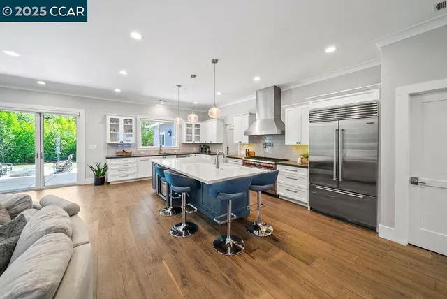 a kitchen with stainless steel appliances a dining table chairs and wooden floor