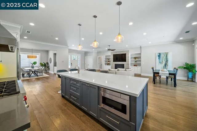 a large kitchen with stainless steel appliances a stove center island a fireplace and a living room view