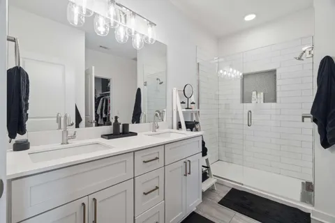 a bathroom with a double vanity sink a toilet and shower