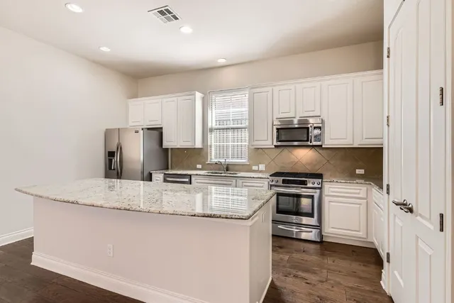 a kitchen with stainless steel appliances granite countertop a stove a sink and a refrigerator