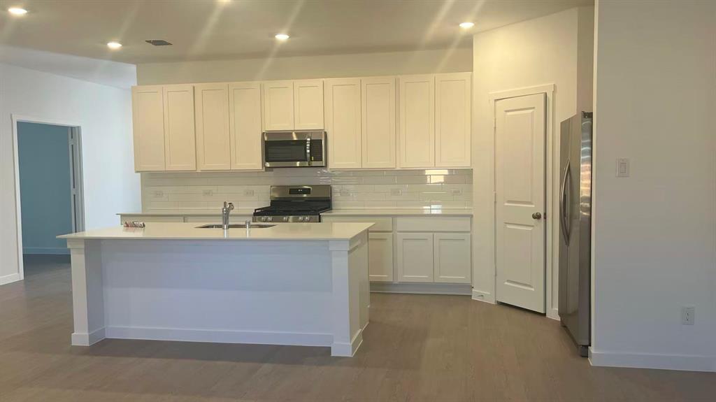 909 Calley Pear Trail Princeton, TX 75407 - Photo 7 of 17 a kitchen with stainless steel appliances granite countertop a stove a sink and a refrigerator with white cabinets