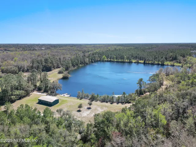 an aerial view of a houses with a yard and lake