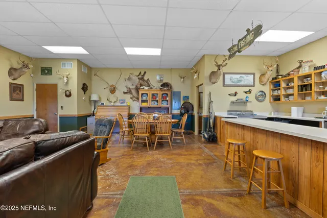 a living room with furniture kitchen view and a wooden floor