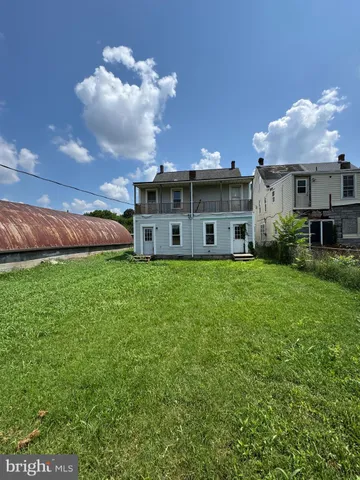 a view of a house with a big yard and large trees