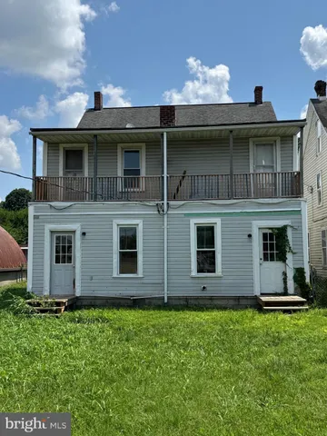 a view of a house with potted plants and a yard