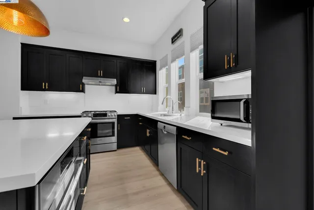 a kitchen with stainless steel appliances a stove microwave and sink