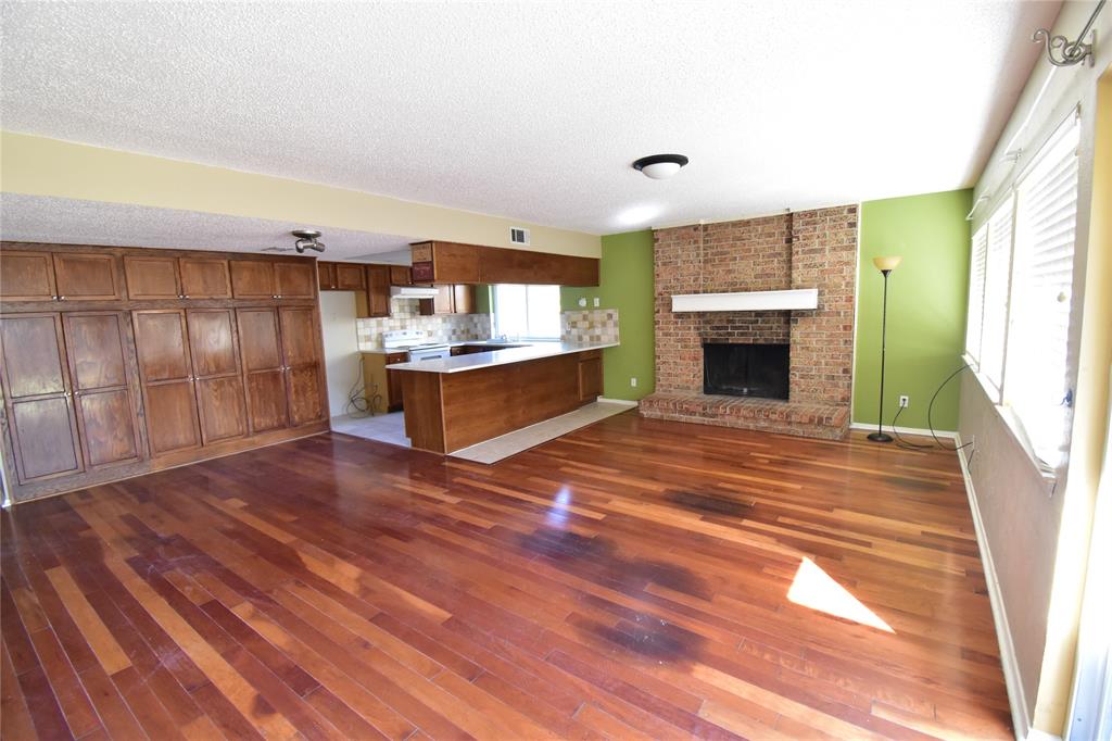 5414 Castleview Lane Garland, TX 75044 - Photo 5 of 20 Unfurnished living room featuring a fireplace, dark wood finished floors, and a textured ceiling