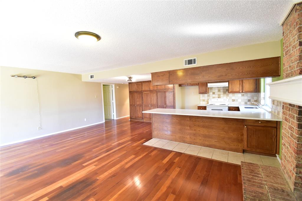 5414 Castleview Lane Garland, TX 75044 - Photo 6 of 20 Kitchen with brown cabinetry, light wood-type flooring, electric range, backsplash, and a peninsula