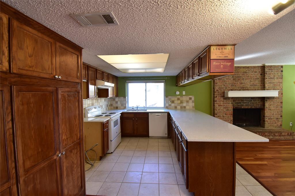 5414 Castleview Lane Garland, TX 75044 - Photo 8 of 20 Kitchen with light tile patterned floors, white appliances, a peninsula, a textured ceiling, and decorative backsplash