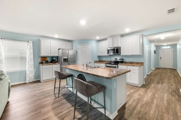 a kitchen with kitchen island granite countertop a sink and a refrigerator