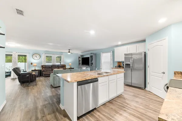 a large kitchen with a stove a refrigerator a sink dishwasher a dining table and chairs with wooden floor