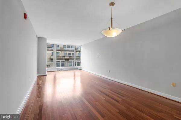 a view of an empty room with window and wooden floor