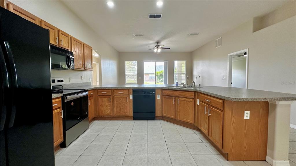 60 Pine Grove Drive Palm Coast, FL 32164 - Photo 17 of 20 a large kitchen with stainless steel appliances kitchen island granite countertop a stove a sink dishwasher and a refrigerator