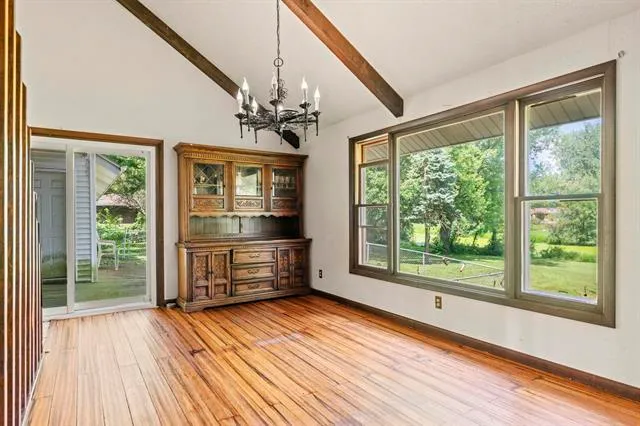 a view of an empty room with glass door and wooden floor