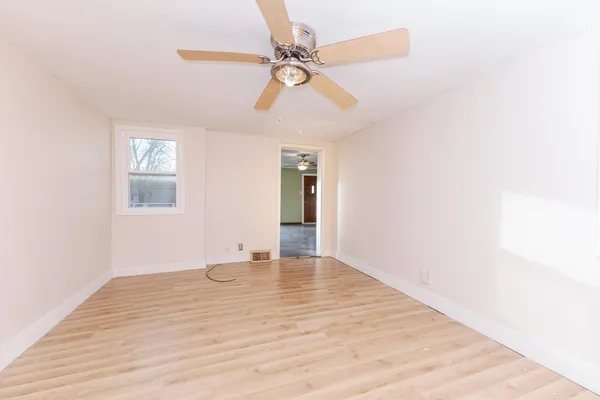 a view of an empty room with window and a ceiling fan
