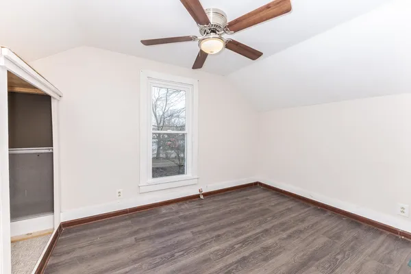 an empty room with wooden floor fan and windows
